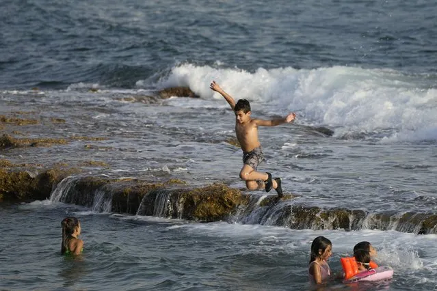 A boy jumps in the water on Batroun beach in Batroun village, north of Beirut, Lebanon, Friday, July 2, 2021. (Photo by Hassan Ammar/AP Photo)