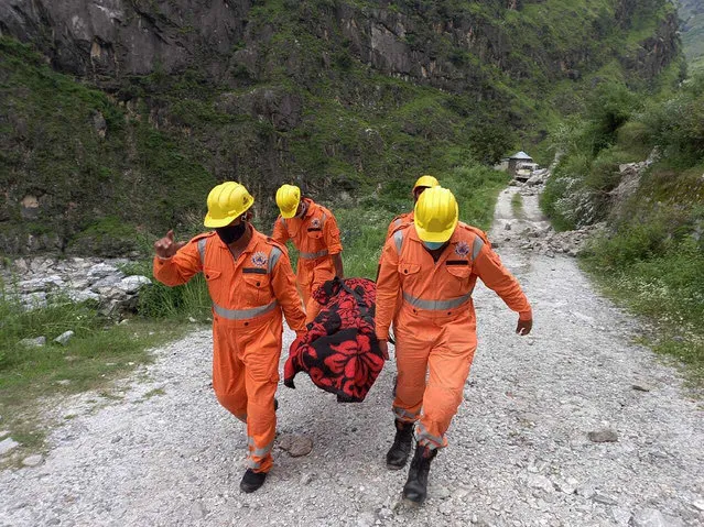 This photograph provided by India's National Disaster Response Force (NDRF) shows NDRF soldiers carrying the body of a victim from the site of a landslide in Kinnaur district in the northern Indian state of Himachal Pradesh, Wednesday, August 11, 2021. A landslide struck several vehicles traveling on a highway in the hills of northern India on Wednesday, trapping as many as 50 people, officials said. (Photo by National Disaster Response Force via AP Photo)