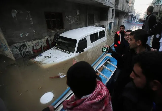 Palestinian rescue volunteers ride a boat through flooded homes in Gaza City, Monday, December 16, 2013. Rescue workers evacuated thousands of Gaza Strip residents from homes flooded by heavy rain, using fishing boats and heavy construction equipment to pluck some of those trapped from upper floors. (Photo by Adel Hana/AP Photo)