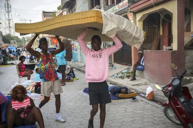 Men carry a mattress as people sleep on the streets after Saturday´s  7.2 magnitude earthquake in Les Cayes, Haiti, Sunday, August 15, 2021. (Photo by Joseph Odelyn/AP Photo)