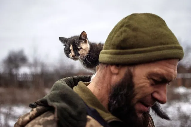 A cat sits on the shoulder of Ukrainian serviceman Mykyta of the 93rd separate mechanized brigade at a rest house near the front line in the Donetsk region on December 25, 2023. (Photo by Thomas Peter/Reuters)