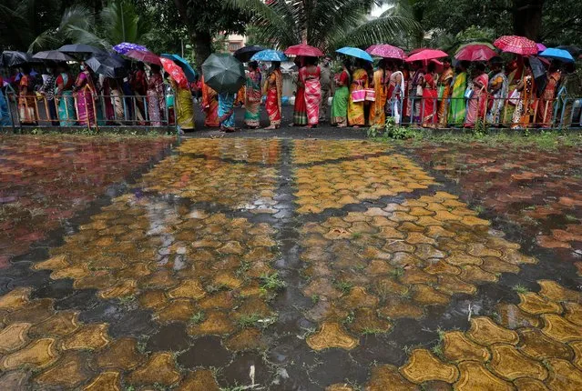 Women hold umbrellas to cover from rain as they wait to receive a dose of COVISHIELD vaccine, a coronavirus disease (COVID-19) vaccine manufactured by Serum Institute of India, outside a vaccination centre in Kolkata, India, August 31, 2021. (Photo by Rupak De Chowdhuri/Reuters)