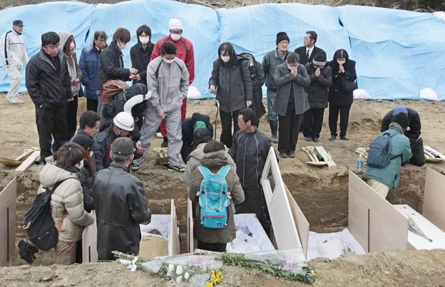 In this March 22, 2011 file photo, family members pay their final respects during a burial ceremony for the March 11 tsunami victims in Higashimatsushima, Miyagi Prefecture, northeastern Japan. “You never know what is going to touch you. For me, it was a group of families wearing pajamas and track suits on a snowy morning in Higashimatsushima, one of the hard-hit coastal cities. They were lined up along trenches dug by backhoe in a city dump. The soldiers filled the trenches one by one, lowering in plain wooden coffins numbered with magic marker. (Photo by Mark Baker/AP Photo)