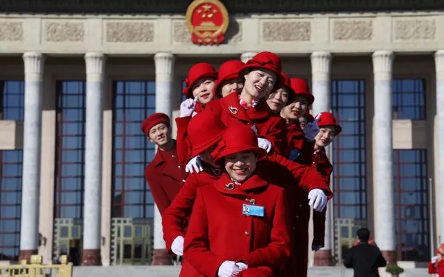 Chinese bus ushers pose for photos outside the Great Hall of the People during a plenary session of the National People's Congress held in Beijing, China, Tuesday, March 12, 2019. The country's top judge and head prosecutor delivered reports to the nearly 3,000 members of the ceremonial legislature on their accomplishments over the past year in curbing crime and prosecuting wrong doers, along with their plans for the year ahead. (Photo by Ng Han Guan/AP Photo)