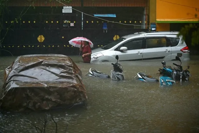 A resident wades through a flooded street after heavy rains in Chennai, India on December 4, 2023. Cyclone Michuang is expected to make landfall on December 5 along the southern coast. (Photo by R. Satish Babu/AFP Photo)