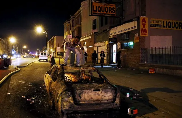 A rioter screams from atop a burning car during clashes in Baltimore, Maryland April 27, 2015. (Photo by Jim Bourg/Reuters)
