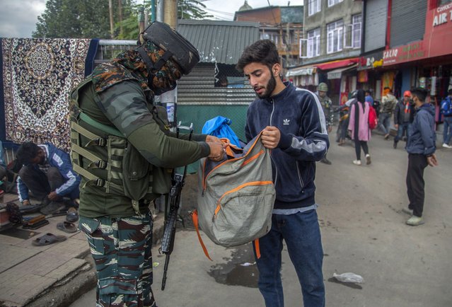 An Indian paramilitary soldier checks the bag of a Kashmiri man at a busy market in Srinagar, Indian controlled Kashmir, Monday, October 11, 2021. The government forces have beefed up security in the region’s main city following a string of targeted killings last week. (Photo by Mukhtar Khan/AP Photo)