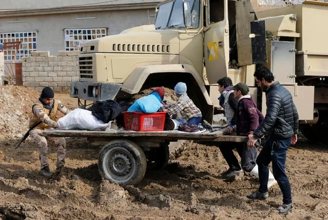 An Iraqi soldier helps people during a fight with Islamic State militants in Rashidiya, North of Mosul, Iraq, January 30, 2017. (Photo by Muhammad Hamed/Reuters)