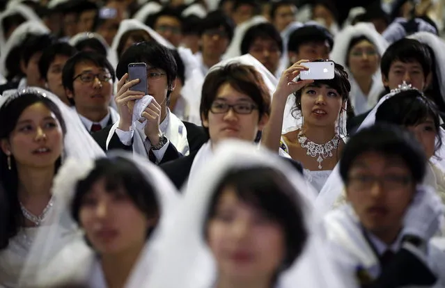 A newlywed couple takes photographs as they attend a mass wedding ceremony of the Unification Church at Cheongshim Peace World Centre in Gapyeong, about 60 km (37 miles) northeast of Seoul February 12, 2014. (Photo by Kim Hong-Ji/Reuters)