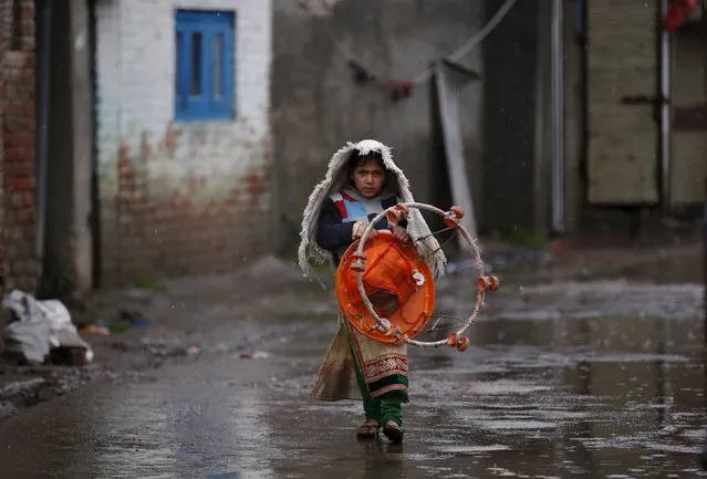 A girl carrying a baby walker walks in an alley as it rains in Srinagar March 17, 2016. (Photo by Danish Ismail/Reuters)
