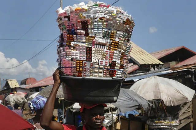 A street vendor carries medicine pills at the Croix des Bosalles market in the La Saline neighborhood of Port-au-Prince, Haiti, Wednesday, November 3, 2021. (Photo by Joseph Odelyn/AP Photo)