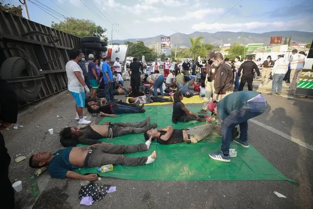 Injured migrants are cared for on the side of the road next to the overturned truck on which they were traveling near Tuxtla Gutierrez, Chiapas state, Mexico, December 9, 2021. Mexican authorities say at least 49 people were killed and dozens more injured when the truck carrying the migrants rolled over on the highway in southern Mexico. (Photo by AP Photo/Stringer)