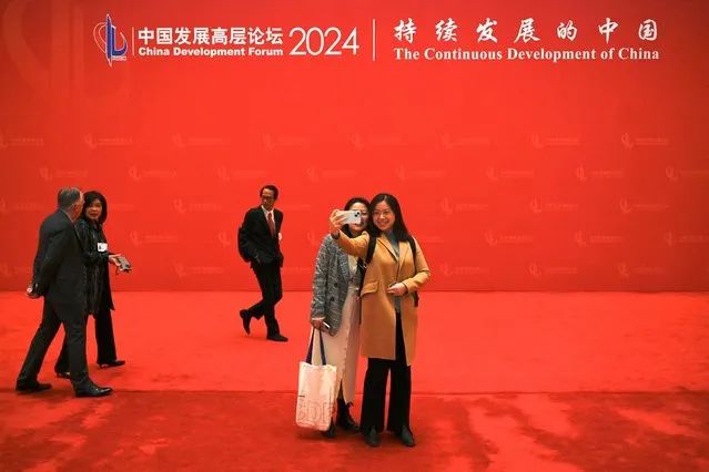 Attendees pose for a selfie at the China Development Forum in Beijing on March 25, 2024. (Photo by Pedro Pardo/AFP Photo)