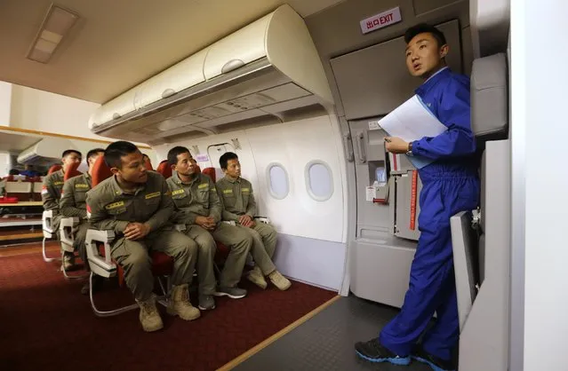 Trainees of the Tianjiao Special Guard/Security Consultant bodyguard training camp listen to an instructor about how to open a cabin door inside a scale model of a passenger jet during a course on emergency evacuation at a flight attendant training centre on the outskirts of Beijing, March 18, 2014. (Photo by Jason Lee/Reuters)