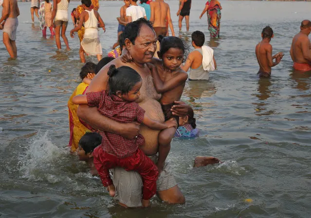 A man carries his children to take a dip in the river Ganges on Somvati Amavasya, or no moon day, in Allahabad, India, Monday, May 18, 2015. (Photo by Rajesh Kumar Singh/AP Photo)