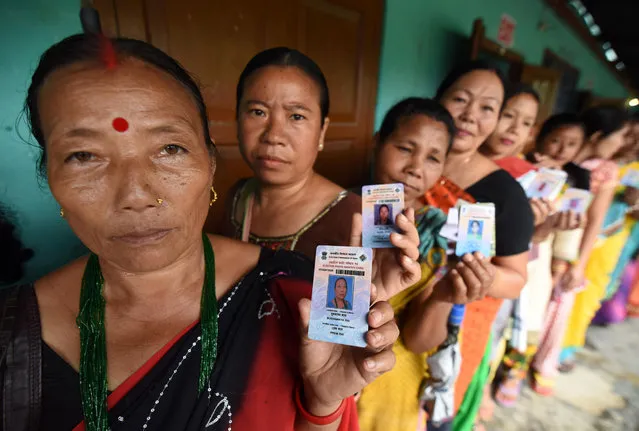 Indian voters pose for a photograph with their identity cards as they queue to cast their ballots in the state assembly elections at a polling station in Diphu in the Karbi Anglong district some 215 kms from Guwahati on April 4, 2016. Millions of Indians head to the polls April 4 in two key state elections, with Prime Minister Narendra Modi's Hindu nationalists facing a tough battle against regional rivals to tighten their grip on power. (Photo by Biju Boro/AFP Photo)