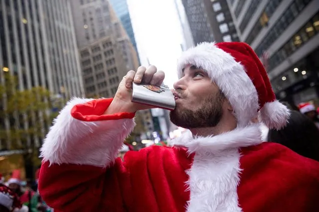 A reveler wearing a Santa Claus costume drinks on a sidewalk during SantaCon in New York City, New York, U.S., December 11, 2021. (Photo by Jeenah Moon/Reuters)