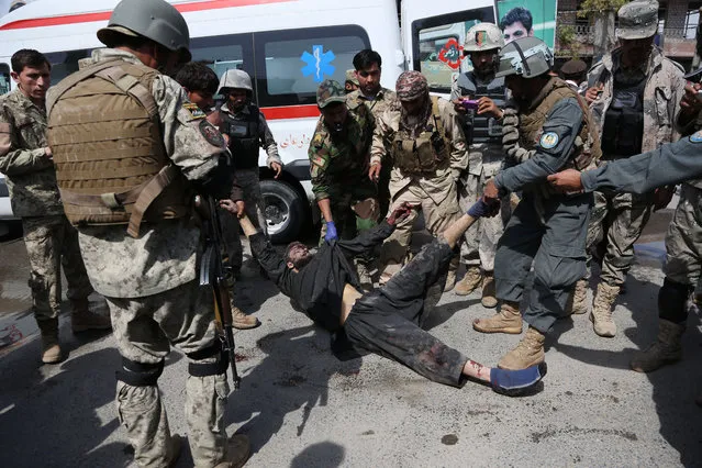 Afghan army and police officers move the body of an insurgent from the scene after the Taliban staged an attack on a police station in Jalalabad, eastern Afghanistan, Thursday, March 20, 2014. A suicide car bomber blew up his vehicle near a police station in eastern Afghanistan while other Taliban insurgents stormed the building Thursday, killing nearly a dozen police officers and a civilian, officials said. (Photo by Rahmat Gul/AP Photo)