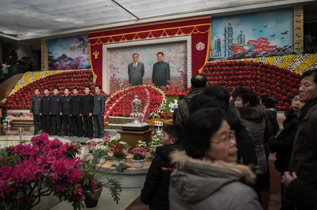 Visitors queue to have their portraits taken at the entrance to a flower show celebrating the 75th anniversary of the birth of Kim Jong-Il in Pyongyang on February 17, 2017. Around 700,000 people are expected to cram into the exhibition hall in Pyongyang over seven days, and its passages were packed on February 17 as soldiers and civilians made their way past the displays, many in jovial mood. (Photo by Ed Jones/AFP Photo)