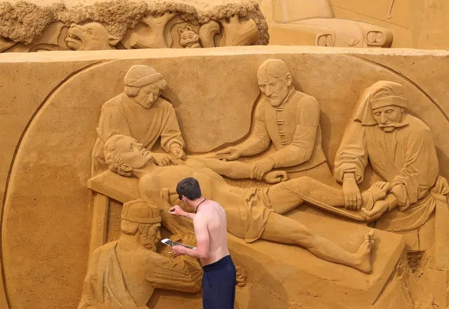 A sand carver works on a sculpture during the Sand Sculpture Festival “Dreams” in Ostend, Belgium on June 18, 2019. (Photo by Yves Herman/Reuters)