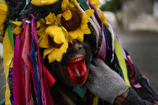 A man dressed as a “bolero” sticks out his tongue during celebrations marking Holy Innocents Day which commemorates King Herod's infanticide of baby boys in Bethlehem after the birth of Jesus according to the Gospel of Matthew, in Caucagua, Venezuela, Tuesday, December 28, 2021. Residents celebrate a variation of the feast day wearing old clothes, painting their faces black and tongues red. The more than 200-year-old tradition is a day of song, dance and pranks. (Photo by Matias Delacroix/AP Photo)