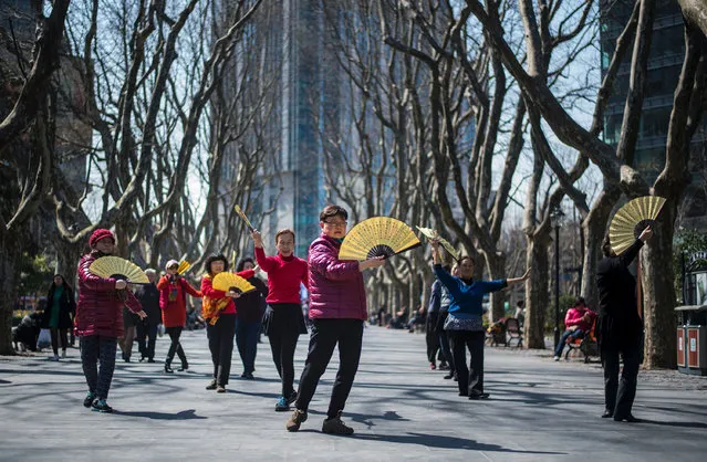 Women dance with fans in a park on a sunny day in Shanghai on March 15, 2017. (Photo by Johannes Eisele/AFP Photo)