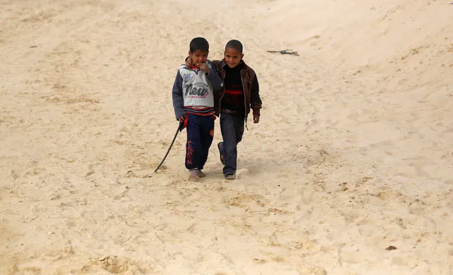 Faysal (L), a 7-year-old jockey, walks with his brother Amin during the opening of the International Camel Racing festival at the Sarabium desert in Ismailia, Egypt, March 21, 2017. (Photo by Amr Abdallah Dalsh/Reuters)