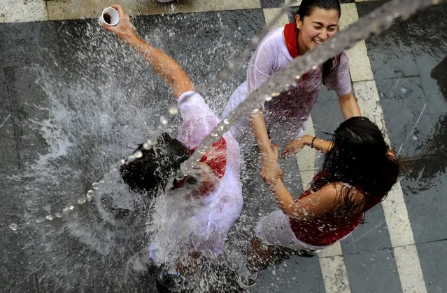 Revellers cool off with water thrown from a balcony at the start of the San Fermin festival in Pamplona, Spain, July 6, 2015. (Photo by Eloy Alonso/Reuters)