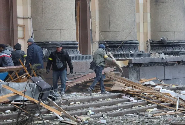 People remove debris outside the regional administration building, which city officials said was hit by a missile attack, in central Kharkiv, Ukraine, March 1, 2022. (Photo by Vyacheslav Madiyevskyy/Reuters)