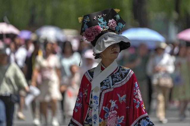 A woman wearing a hat and dressed in traditional costume visits the Forbidden City in a hot and sunny day in Beijing, Sunday, June 9, 2024. (Photo by Andy Wong/AP Photo)