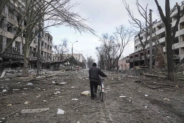 A man walks with a bicycle in a street damaged by shelling in Mariupol, Ukraine, Thursday, March 10, 2022. (Photo by Evgeniy Maloletka/AP Photo)
