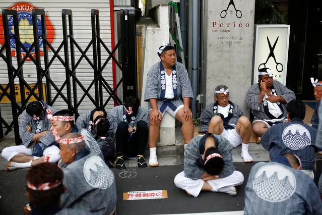 Men sit in the shade as they rest after carrying a portable shrine, a Mikoshi, during the Sanja festival in Tokyo's Asakusa district, Japan, May 15, 2016. (Photo by Thomas Peter/Reuters)