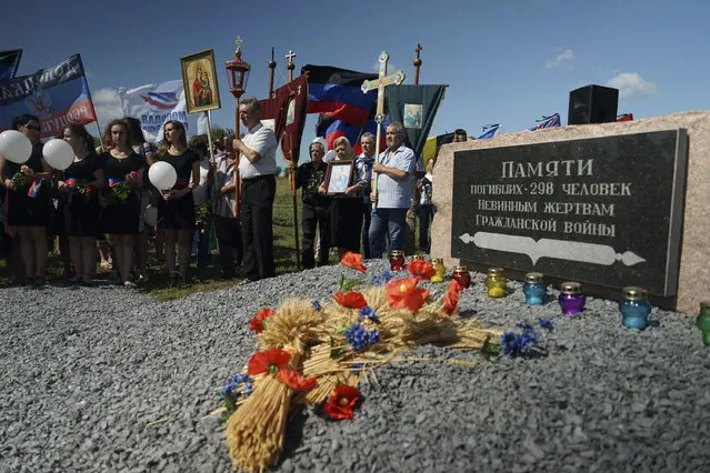 People stand with Orthodox crosses and icons as they attend a memorial service at the crash site of the Malaysia Airlines Flight 17, near the village of Hrabove, eastern Ukraine, Friday, July 17, 2015. In a solemn procession, residents of the Ukrainian village where a Malaysian airliner was shot down with 298 people aboard a year ago marched Friday to the crash site. (Photo by Mstyslav Chernov/AP Photo)