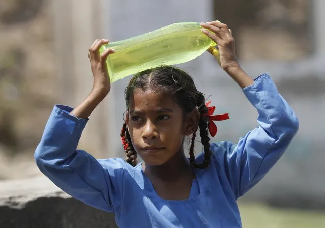 An Indian school girl cools her head with a cold water bottle in Jammu, India, Thursday, May 19, 2016. Scorching summer temperatures, hovering well over 40 degrees Celsius, (104 Fahrenheit) are making life extremely tough for millions of people across north India. (Photo by Channi Anand/AP Photo)