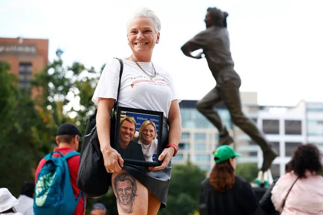 A member of the public with a Shane Warne tattoo poses in front of a statue of Shane Warne before the state memorial service for former Australian cricketer Shane Warne at the Melbourne Cricket Ground on March 30, 2022 in Melbourne, Australia. Warne died suddenly aged 52 on Friday 4 March while on holiday in Thailand. (Photo by Daniel Pockett/Getty Images)