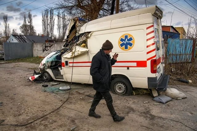 A local man walks past a damaged ambulance, as Russia's attack on Ukraine continues, in the settlement of Hostomel, outside Kyiv, Ukraine on April 6, 2022. (Photo by Vladyslav Musiienko/Reuters)
