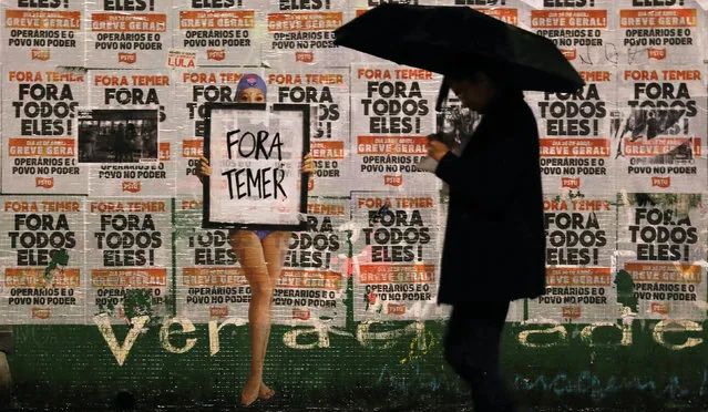People walk past a sign reading  “Out Temer” at the end of a protest against Brazil's President Michel Temer in Sao Paulo, Brazil, May 21, 2017. (Photo by Nacho Doce/Reuters)