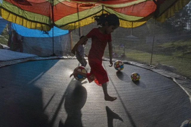 A girl plays on a trampoline at a local fair in Paror, about 40 kilometers (25 miles) south of Dharmsala, India, Tuesday, March 22, 2022. These local fairs, once an annual feature, are slowly returning after being cancelled during the Covid pandemic. (Photo by Ashwini Bhatia/AP Photo)