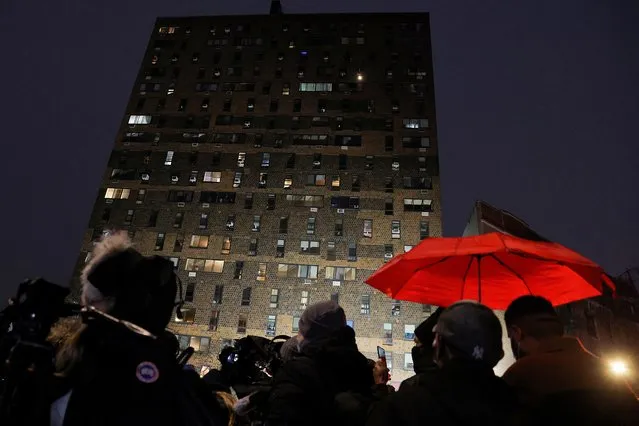 People stand outside an apartment building where a fire occurred in the Bronx borough of New York City, U.S., January 9, 2022. (Photo by Andrew Kelly/Reuters)