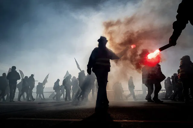 Protesters hold flares during a demonstration on December 10, 2019 in Lyon as part of the sixth day of massive strike action over government's plans to overhaul the pension system. French unions have vowed to keep up the fight over the reforms, which are set to be finalised and published on December 11, with mass demonstrations in Paris and other cities, with teachers and other workers who once again have walked out alongside transport workers. (Photo by Jeff Pachoud/AFP Photo)