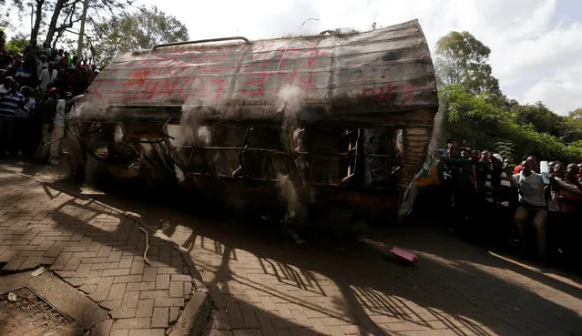 Members of Kenya's ruling Jubilee coalition dump the wreckage of a burnt mini-bus outside the office of opposition leader of the Coalition for Reforms and Democracy (CORD), Raila Odinga (not in the picture), as they demonstrate in support of the Independent Electoral and Boundaries Commission (IEBC) the electoral body ahead of next year's election in Nairobi, Kenya, June 8, 2016. (Photo by Thomas Mukoya/Reuters)