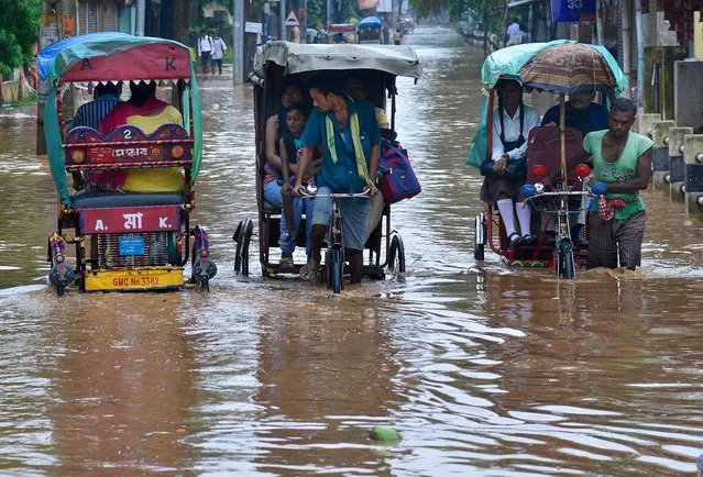 People crossing a waterlogged street in rickshaws caused by heavy monsoon rain in Guwahati city, Assam, India, 22 June 2017. One more person died in Assam due to electrocution in a flooded street in Guwahati city as ongoing torrential monsoon showers caused flash flooding in parts of Assam and Mizoram states, killing at least 13 people and disturb the normal life over the week in the northeastern region of India. (Photo by EPA/Stringer)