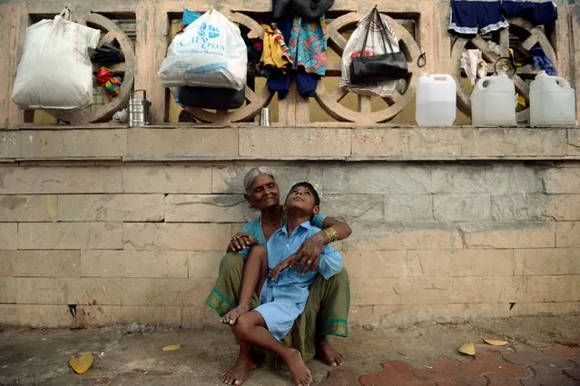 In this photograph taken on May 20, 2014 nine year old Indian boy Lakhan Kale sits with his grandmother on the pavement in Mumbai. (Photo by Punit Paranjpe/AFP Photo)