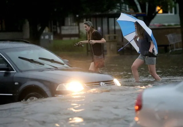 Pedestrians and motorists attempt to navigate the flooded intersection of University Boulevard and North Midvale Road in Madison, Wis., after heavy rain moved through the area Monday, June 30, 2014. Severe thunderstorms packing high winds and heavy rain have downed trees and power lines all across southern Wisconsin. (Photo by John Hart/AP Photo/Wisconsin State Journal)