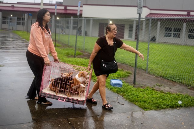 Jeny Gomez, left, and her mother, Paula Cosa, carry a crate with dogs into Middleton High School, which is open as a shelter in Tampa on Wednesday, October 9, 2024. (Photo by Kathleen Flynn for The Washington Post)