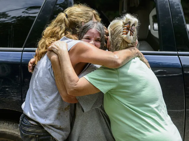 Kathy Bostic, left, Lula Allen, center, and Mildred Hayes embrace outside of Bostic's home, which was destroyed form heavy rains and flooding, along Jordan Creek Road in Elkview, W.Va., Friday, June 24, 2016. They all live along Jordan Creek road and have been dealing with varying levels of damage to homes and the road. (Photo by Sam Owens/Charleston Gazette-Mail via AP Photo)
