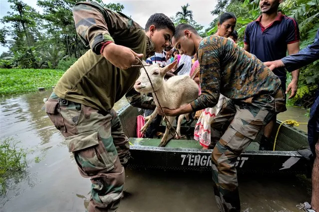 Indian army personnel rescue flood affected villagers and animals on a boat in Jalimura village, west of Gauhati, India, Saturday, June 18, 2022. More than a dozen people have died as massive floods ravaged northeastern India and Bangladesh, leaving millions of homes underwater and severing transport links, authorities said Saturday. (Photo by Anupam Nath/AP Photo)