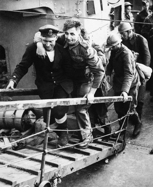 A sailor assisting a wounded soldier, followed by French Troops on return to England, on June 1, 1940. (Photo by AP Photo)