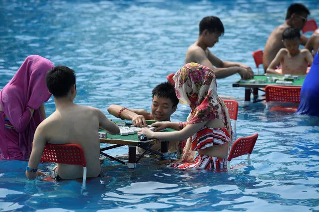 People play mahjong as they sit in water at a water park on a hot day in Chongqing, China August 2, 2017. (Photo by Reuters/China Stringer Network)