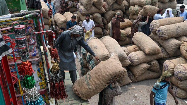 Labourers unload sacks of potatoes from a truck at a local market in Lahore on July 9, 2024. (Photo by Arif Ali/AFP Photo)